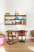Retro chairs and table below toys on String shelves