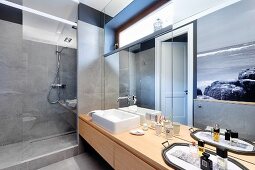Mirrored wall above washstand with countertop sink next to walk-in shower