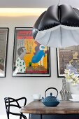 Black and white pendant lamp with inflatable lampshade above dining table in front of row of pictures on wall