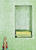 Badezimmer mit grünen Mosaikfliesen, in Wandnische Handtücher