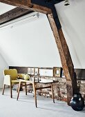 60s table and chair against brick knee wall in converted attic with original old roof beams