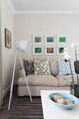 Grey sofa with scatter cushions & tripod, studio-style lamp in modern living room