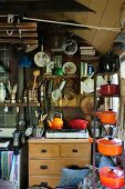 Cooking utensils on shelves and hung on walls in rustic kitchen