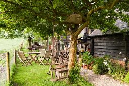 Garden furniture and swing outside wooden house