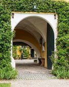 Arched entrance with vaulted ceiling in ivy-covered villa façade