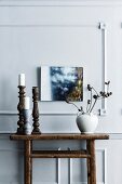 Candle holder and vase with dried flowers on a rustic wooden console table