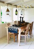 Crystal chandelier over rustic dining table with Balinese batik runner and ethnic-style crockery
