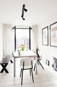 Various black and white chairs and bench around modern dining table in front of open, double balcony doors with view of city