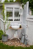 Vintage wash basin and pitcher on rusty metal stand against outer wall of garden shed