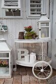 White-painted vintage tea trolley decorated with lantern, potted plants and white jugs