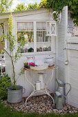 Vintage wash basin and pitcher on rusty metal stand against outer wall of garden shed