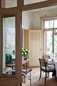 Blick durch offene Tür in Salon mit Essplatz und Armlehnstühlen, an Wand Konsolentisch