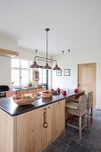 Island counter with wood-clad sides and stone worksurface in rustic kitchen