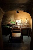 Crystal candelabras, Buddha figurine and bowl of vegetables on wooden table under spotlight in vaulted cellar