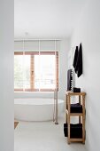Blick in minimalistisches Bad auf freistehende Badewanne mit Standarmatur vor Fenster