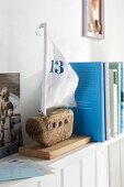 A sailing boat made from driftwood as a book end on a shelf