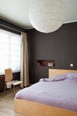Double bed with lilac bed linen in bedroom painted dark brown