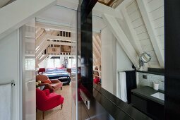 White-painted roof structure and dark installations in attic bathroom with view into bedroom