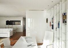 Home office area in open-plan interior with white furnishings, Eames Aluminium Chairs and fitted shelving