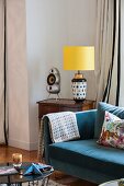 Blue sofa next to table lamp on antique table