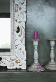 Detail of mirror with ornate, floral wooden frame and vintage-style candlesticks
