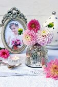 Mercury glass vase and pink dahlias on lace doily and photo of girl in antique picture frame