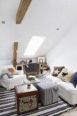 White armchair and sofa around cube table and pouffe in attic room