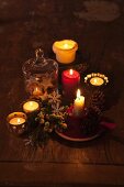Schummriges Licht von brennenden Kerzen und Teelichtern mit weihnachtlicher Deko