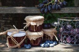Marmeladengläser mit Makramee-Derkoration und Herbstfrüchte auf verwittertem Holzregal