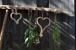 Macrame hearts hung on vintage wooden rake against weathered board wall