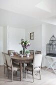 Wooden dining table, antique upholstered chairs and vintage birdcage on tray table in dining room