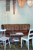 Simple kitchen chairs and leather couch around delicate retro tea trolley