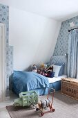 Boy's bedroom in shades of blue with soft toys, patterned wallpaper and vintage-style toys