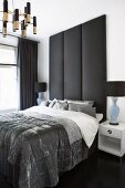 Elegantes Schlafzimmer mit Doppelbett vor hohen, gepolsterten Paneelen
