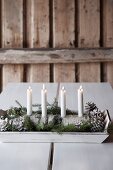 Four white candles in DIY candelabra made from half a birch log on wooden tray