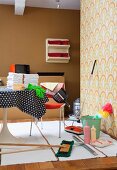 Retro cleaning utensils on woven rug and Tulip table with black and white polka-dot tablecloth; wall in 70s-style brown