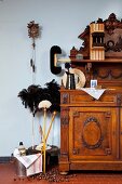 Various cleaning utensils next to antique dresser and cuckoo clock on wall