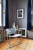 Modern chair with white-painted metal frame in corner of room in front of group of pendant lamps