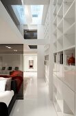 Offener Showroom mit Schlafbereich, seitlich weiße Schrankwand mit Regalöffnungen, in zeitgenössischer Architektur
