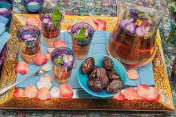 Tray of tea glasses, jug and dates scattered with petals