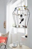 A wire-framed pendent lamp decorated as a birdcage with colourful glass birds
