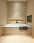 Eingebaute Badewanne in Designerbad mit beigen Riemchenfliesen; Ablagenische mit indirekter Beleuchtung in der Rückwand