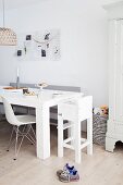 Dining area with white metal mesh pinboard in family-friendly interior with white highchair and basket of toys