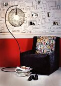 Dark armchair with photo motifs on cushion and standard lamp in front of wallpaper with pattern of picture frames