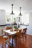 Dining table with wooden top and various chairs in white kitchen