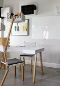 Avant-garde chairs around table and shelf mounted on wooden pole, framed picture and floating shelves in background