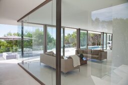 View of elegant living area, terrace and pool through glass walls