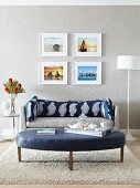 Four pictures above sofa with long patterned bolster behind large leather ottoman