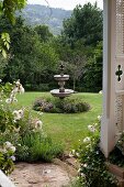 Blick auf Springbrunnen aus Stein in weitläufigem Garten
