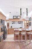Bar stools and pale wooden counter in open-plan kitchen in modern, country-house style